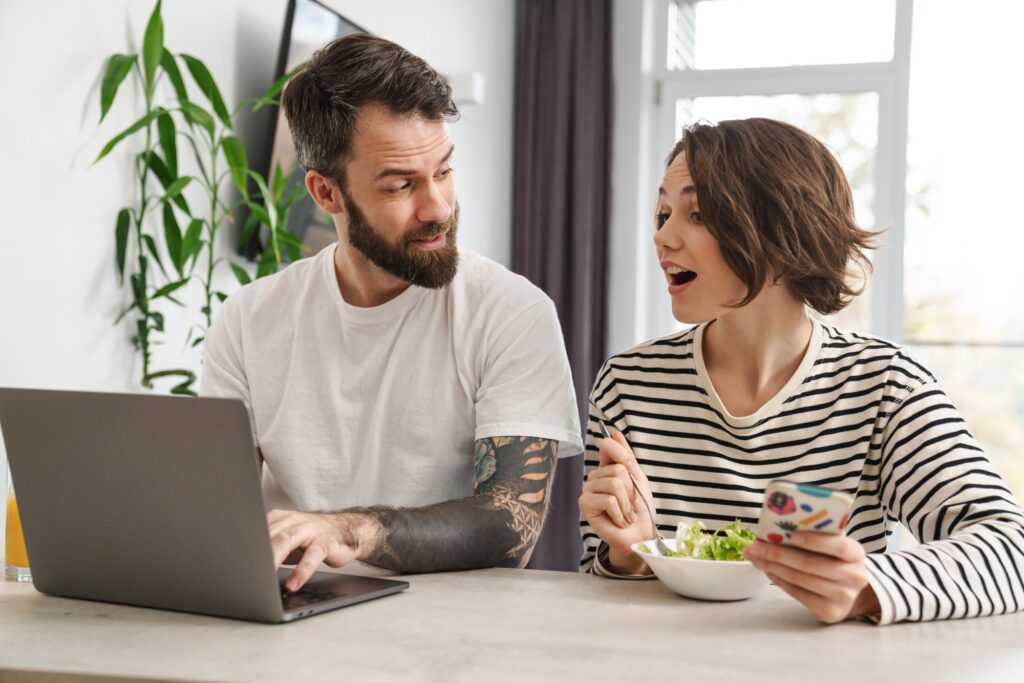Beautiful couple sitting at the kitchen with laptop